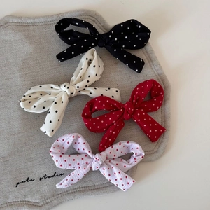 Détail de quatre barrettes à nœuds à pois en noir, blanc, rouge et rose clair