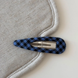 Detailed view of the checkered fabric wrap and silver metal spring on a navy blue BB hair clip