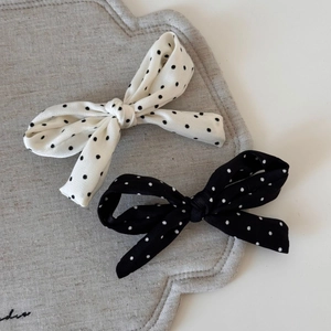 Lot de barrettes à nœuds à pois noir et blanc sur un support en tissu texturé chic