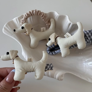 Dettaglio di fermagli per capelli in tessuto a forma di cane con campanelli d'oro