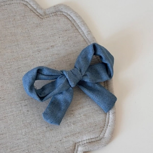 Détail d'une barrette à cheveux nœud en tissu bleu avec texture denim et nœud central