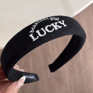 Detail of black sponge headband with white LUCKY and beautiful girl embroidery textures