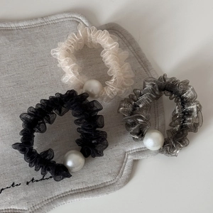 Dettaglio di tre elastici in rete con grandi perle finte in bianco, nero e grigio