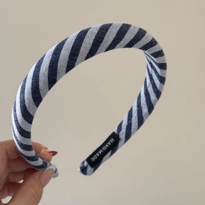 Detailaufnahme von handgefertigtem blau-weiß gestreiftem Stoffstirnband mit Etikett