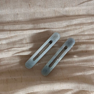 Detail of light blue marble acetate hair clips with silver metal base and logo