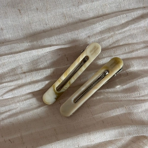 Macro shot of tortoiseshell acetate hair clips with silver metal grip on cream fabric