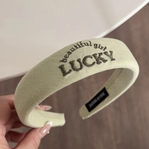 Close-up of LUCKY and Beautiful Girl embroidery on green padded sponge headband