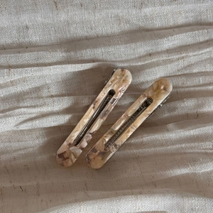 Detail of acetate marble pattern hair clips with France Handmade text on cream fabric