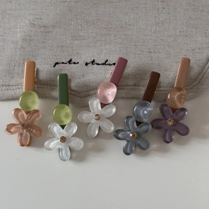 Detalle de cinco pinzas de flores en acrílico colorido con diamantes de imitación