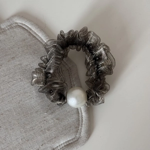 Vista dettagliata dell'elastico in tulle grigio con perla elegante su lino morbido