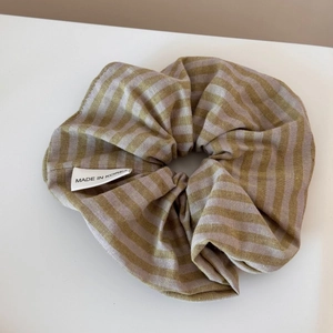 Detail eines gestreiften olivgrünen Scrunchie mit weißem Made in Korea Label aus Seide