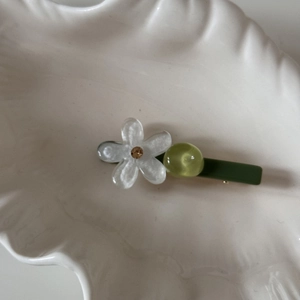 Primer plano de una pinza para el cabello con flores de colores sobre un plato decorativo