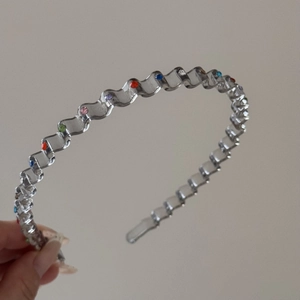 Detail view of wavy metal headband with colorful rhinestones for hair styling