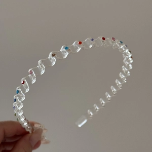 Detail view of transparent wavy headband with multi-color rhinestones in blue and red