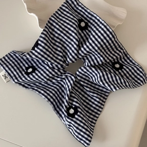 Chic black and white gingham hair scrunchie with floral accents on white ceramic dish