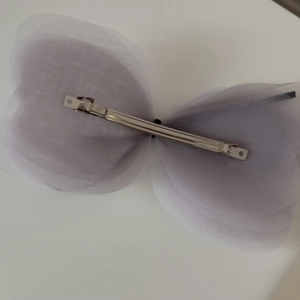 Vue détaillée de la pince en métal argenté sur un nœud papillon en maille multicouche