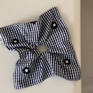 Detail of checkered fabric hair scrunchie with knit flower charm and fine edge stitching