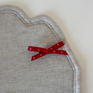 Vue macro du tissu en lin beige avec un nœud papillon rouge à pois blancs en détail