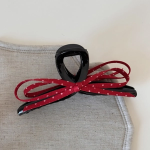 Gros plan d'une pince à cheveux avec nœud à pois rouges sur tissu en lin gris