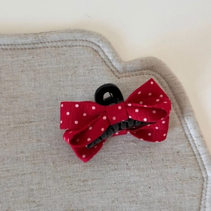 Gros plan d'une pince à cheveux à nœud rouge à pois sur fond de lin montrant la texture