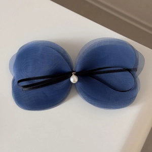 Détail de la pince à cheveux avec nœud en tulle bleu multicouche et perle centrale