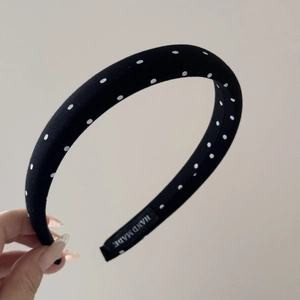Nahaufnahme von schwarzem Stoff-Haarreif mit weißen Punkten und Hand Made Etikett