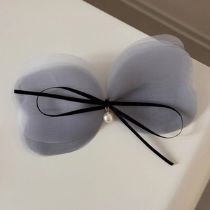 Détail d'une barrette à cheveux avec nœud en maille bleue et pendentif perle élégant