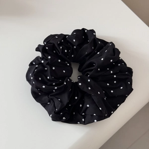 Detailansicht der schwarz-weißen Polka-Dot-Stoffstruktur auf einem breiten Haarband
