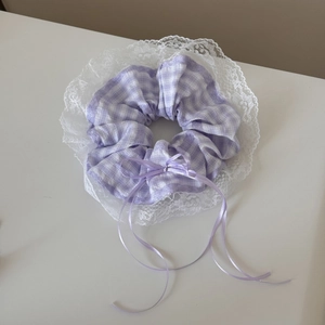 Detailed view of purple plaid scrunchie with white lace trim and satin bow ribbons
