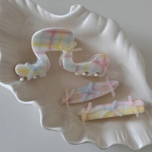 Détail de pinces à cheveux à carreaux pastel avec nœuds en résille sur plateau blanc