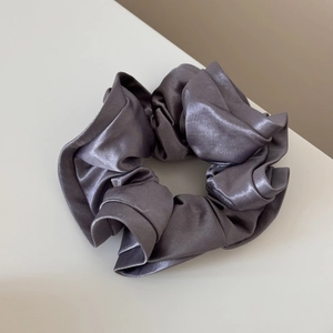 Detail of grey satin scrunchie with a glossy silk texture and elegant ruffled design