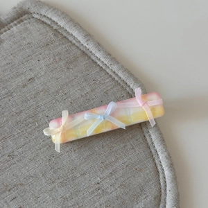 Détail de la pince à cheveux style ballet avec trois nœuds en ruban de soie sur résine crème