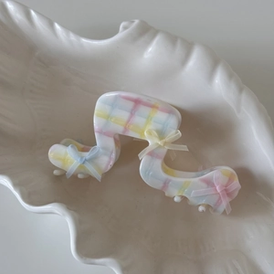 Détail d'une pince à cheveux à carreaux pastel avec des nœuds sur un plateau en céramique