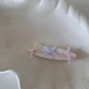 Détail d'une pince à cheveux marbrée pastel avec trois nœuds sur plateau blanc
