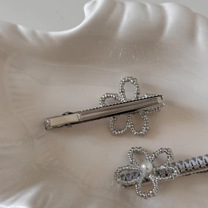 Detail of silver floral hair clip with round pearls and sparkling rectangular rhinestones