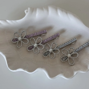 Detailed close-up of crystal flower hair pins with pearls on a decorative tray