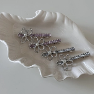 Elegant silver flower hair clips set with pearls and rhinestones on a shell tray