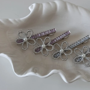 Close-up of four floral pearl and crystal hair clips set in a white ceramic shell tray