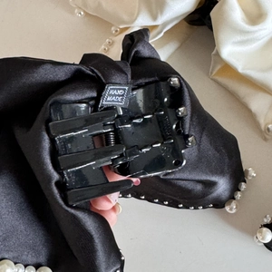 Detail of the handmade woven label on a vintage black satin hair claw with white pearls
