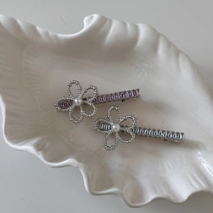 Detail of elegant hair clips with pearl flowers and crystal step-cut stones on a tray