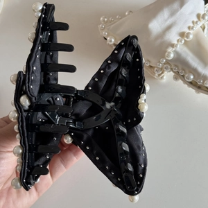 Detailed close-up of large black satin bow hair claw clip with white pearls and rhinestones