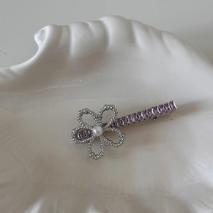 Detail of silver flower hair clip with pearl center and purple zircon baguette crystals