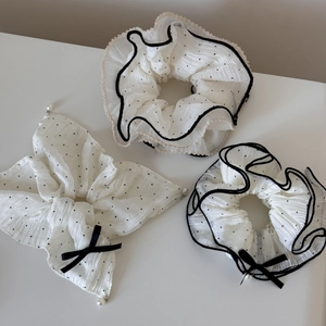 Détail de chouchous en mousseline blanche à pois noirs ornés de perles élégantes