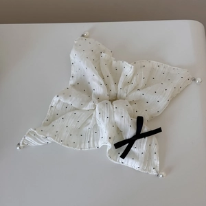 Détail d'un chouchou blanc à pois avec perles fantaisie et un petit nœud en ruban noir