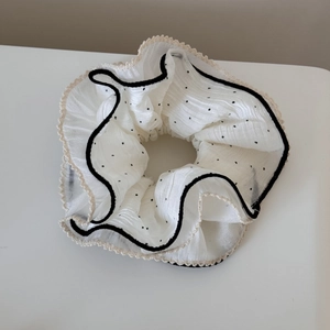 Détails d'un chouchou en mousseline blanche à pois avec bordure en dentelle élégante