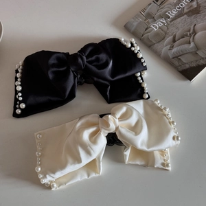 Detail of elegant satin bow hair clips with faux pearl trim in black and cream white colors