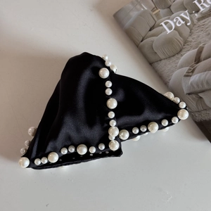 Close-up of black satin hair claw clip with faux pearl embellishments and bow detail