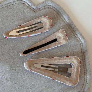 Detailed view of three red polka dot hair clips showing fabric texture and metal backing