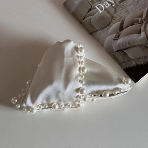 Detail of elegant cream satin heart hair claw clip with faux pearl trim on white backdrop