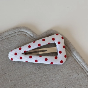 Detail of red polka dot triangle hair clip with textured fabric on a soft background